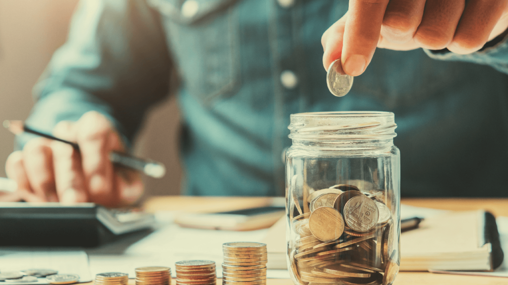 a businessman puts coins in a glass jar