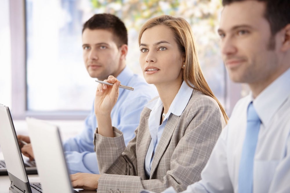 Businesswoman sitting through a demo with coworkers | CRM ROI